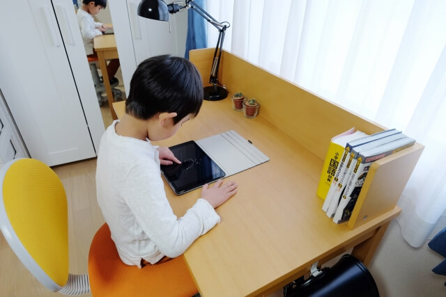 自宅の机でタブレットを使う子供