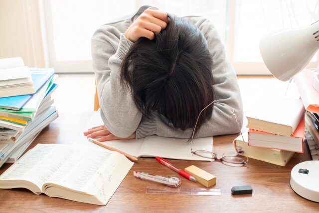 勉強中に机で疲れている学生